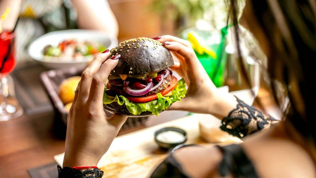 Mujer disfrutando de hamburguesa Labari